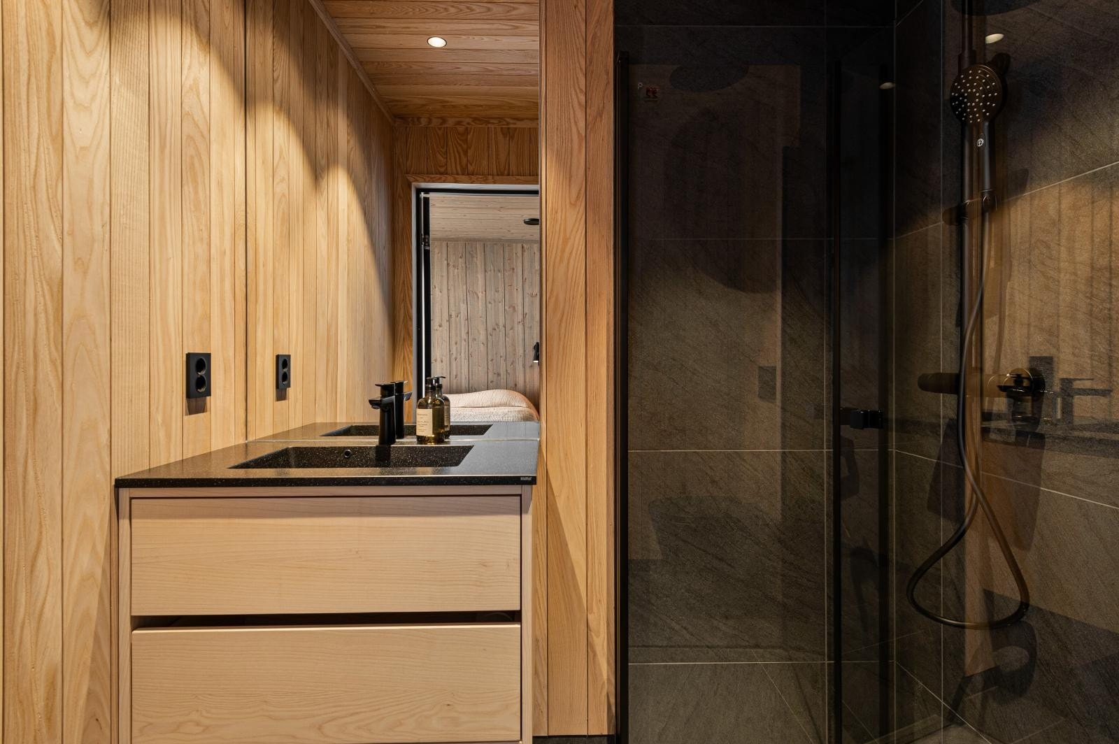 Bad tilhørende hovedsoverommet. Begge bad er levert med moderne VVS-utstyr med sort servantbatteri, sort dusjbatteri med toppdusj og håndholdt løsning samt dusjvegger med sorte profiler/innfestning. Galleribilde