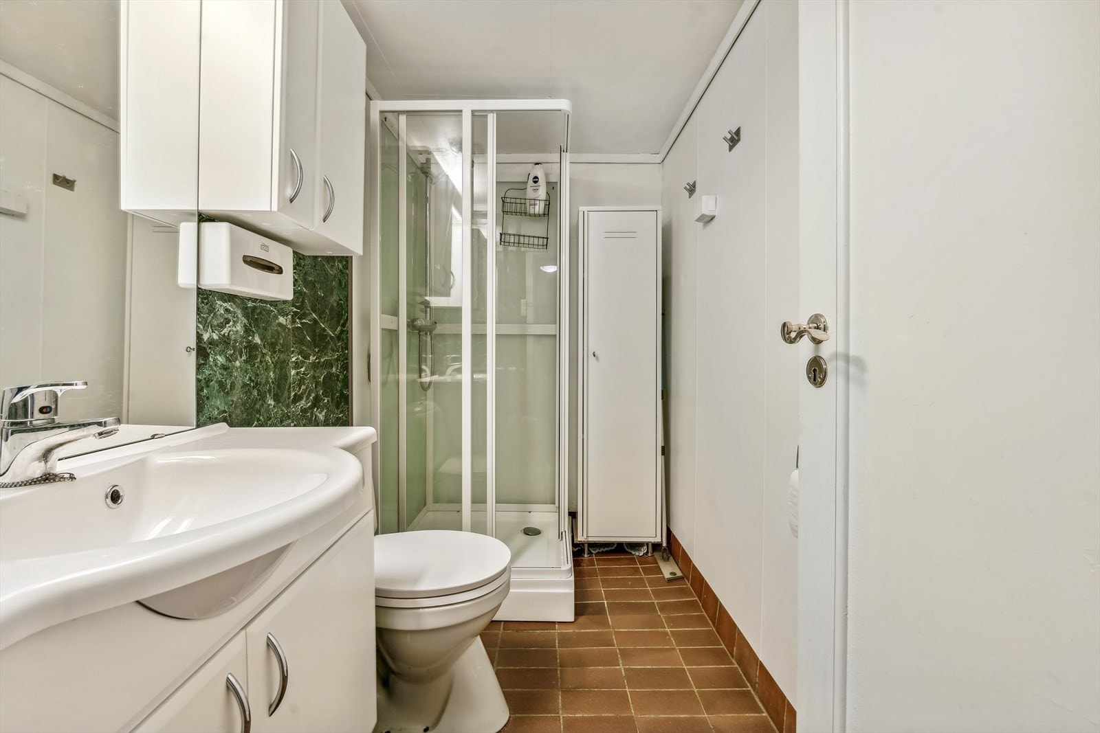 Bad med flis på gulv og våtromsplater på vegg. Godt med skapplass for oppbevaring og dusjkabinett. Galleribilde