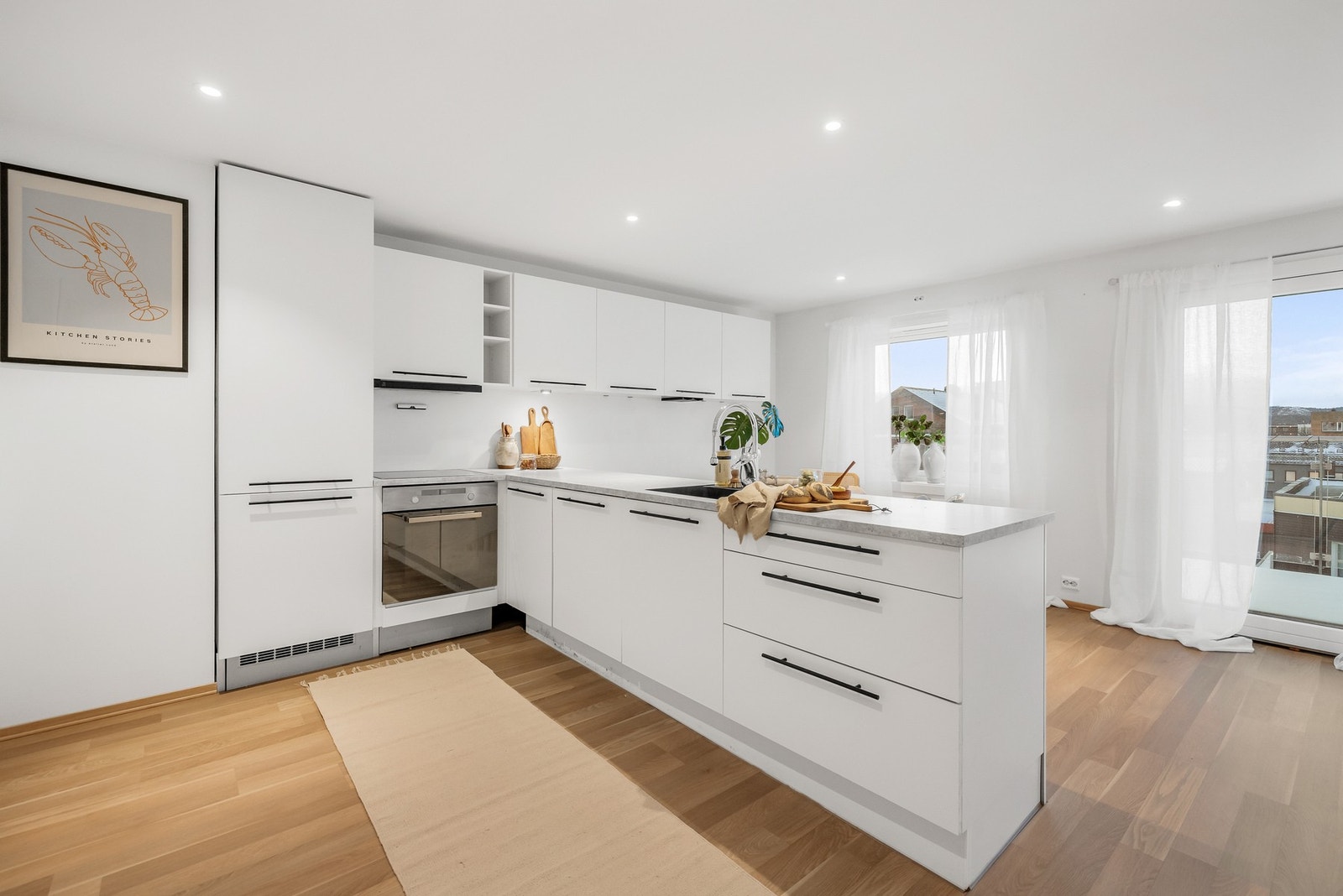 Kjøkken som del av stuen med innredning med glatte lyse fronter og benkeplate av laminat. Galleribilde