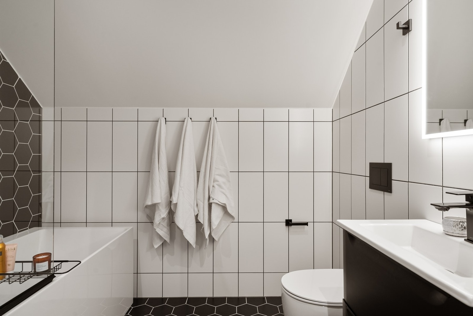 Bad i 2. etg. med badekar, vegghengt toalett, servantskap og speil med lys. Galleribilde