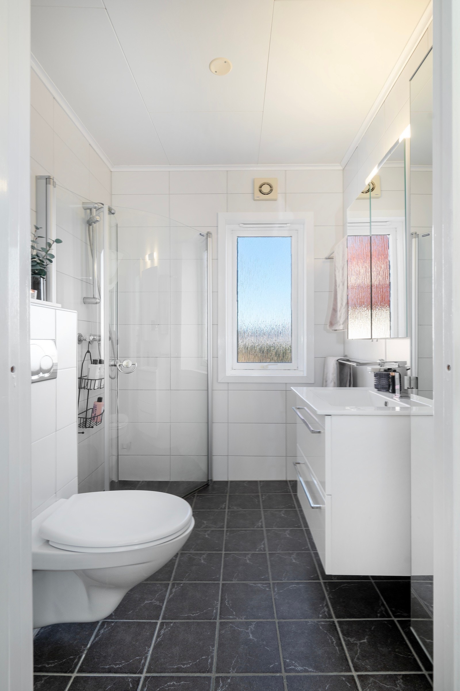 Badet har flislagte overflater og varmekabler i gulvet. Her får man alt man trenger til hektiske morninger eller til en rask dusj etter løpetur på Aksla. Galleribilde