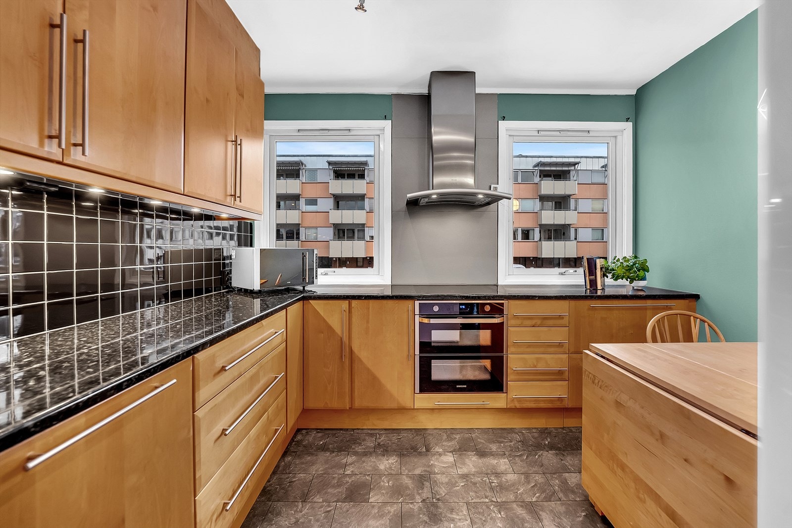 Romslig kjøkkeninnredning med laminert skrog, glatte fronter og stein/komposittplate med kjøkkenkum. Skjulte sokkelskuffer og masse skapplass! Galleribilde