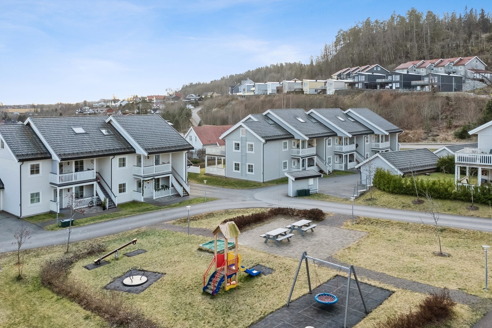 Sameiet har ett hyggelig fellesareal med lekeapparater og med hyggelige sittebenker Galleribilde