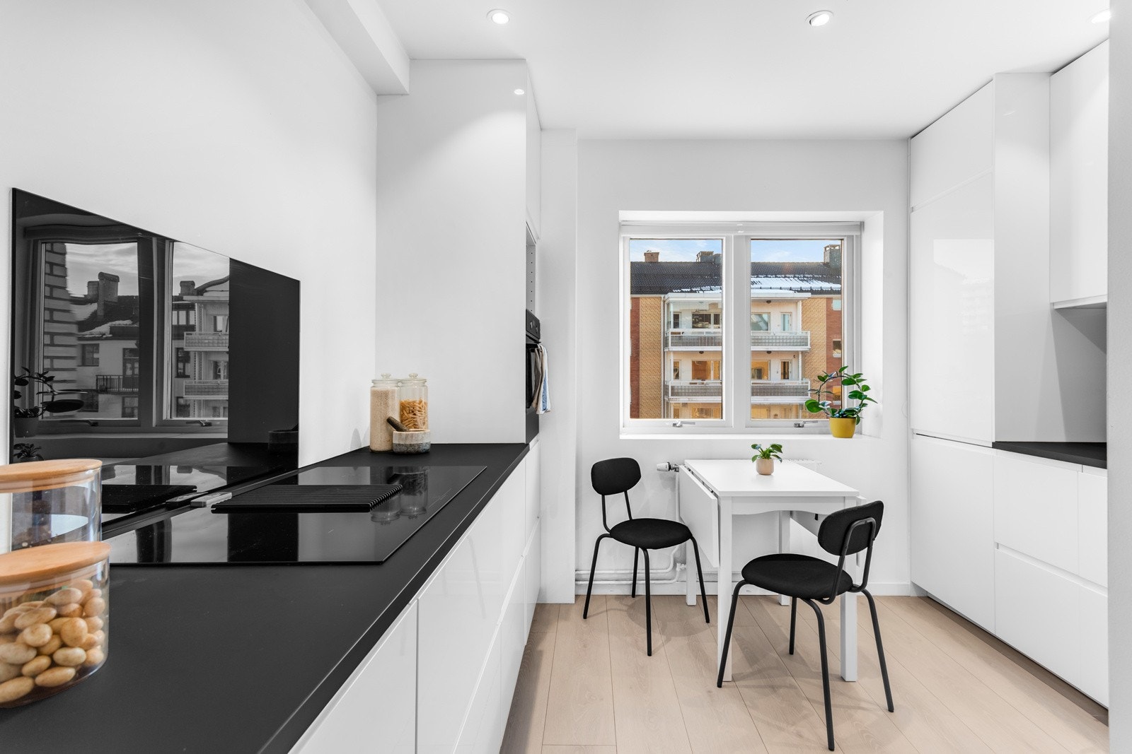 Stilren takhøy kjøkkeninnredning med hvite fronter med innfreste håndtak. Galleribilde