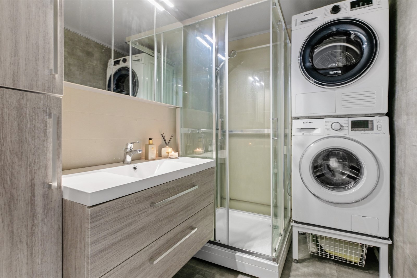 Bad med dusjkabinett. Praktisk servantskap med skuffer samt høyskap i samme stil. Opplegg for vask/tørk. Galleribilde