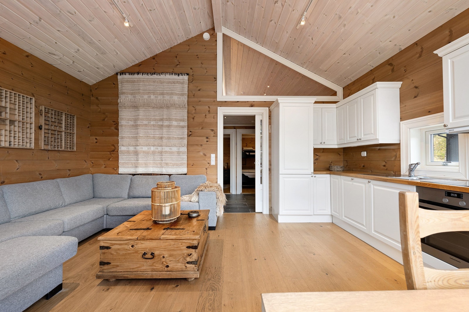 Stue, spisestue og kjøkken i åen løsning. Vindu mot hems og dør med glassfelt mot entre/gang Galleribilde