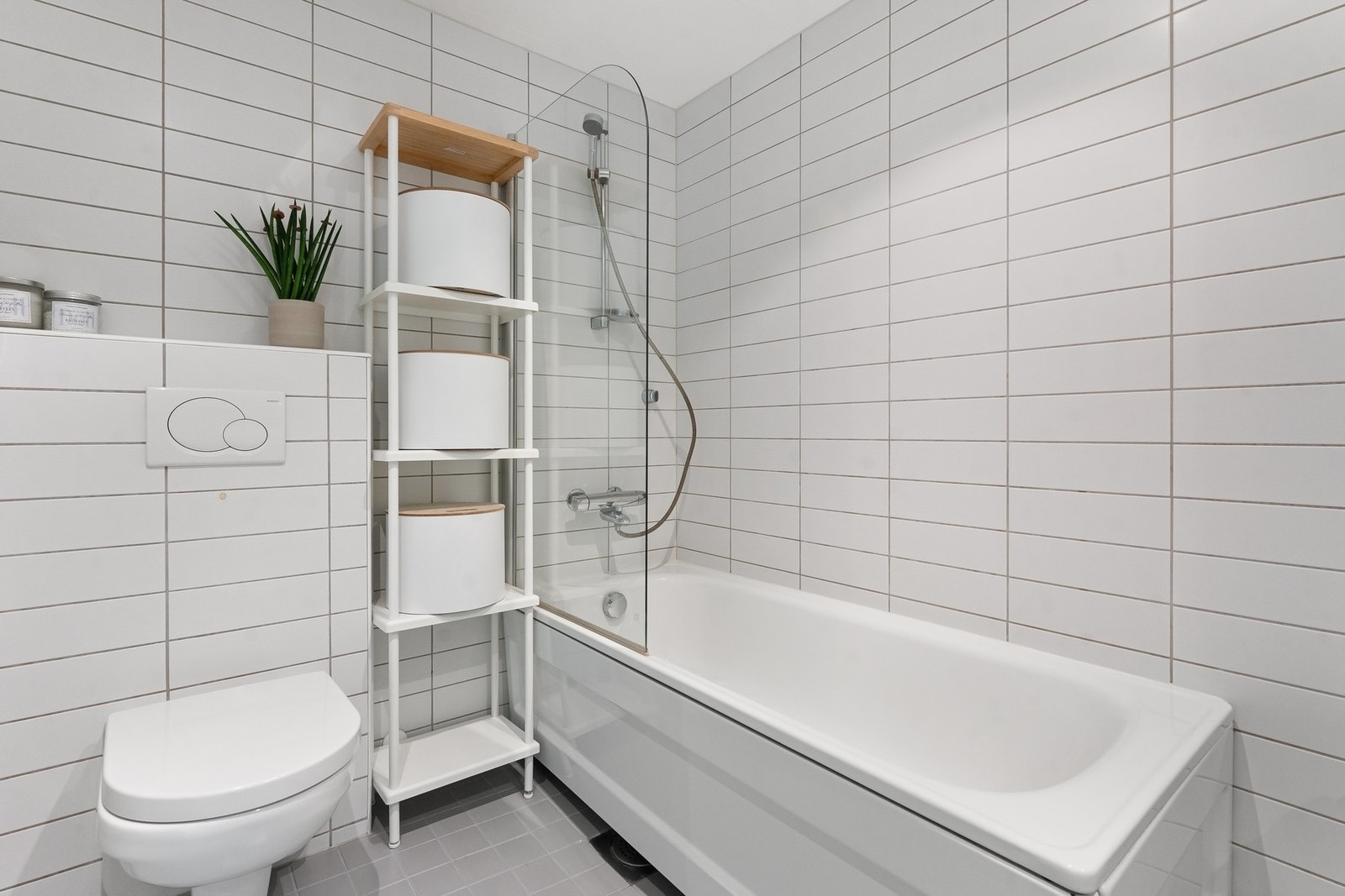 Videre er det vegghengt toalett og badekar med dusjarmatur samt glassvegg. Galleribilde