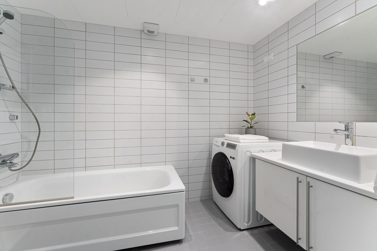 Boligens baderom er bygget opp med lyse fliser på vegger og grå fliser på gulv. Baderommet har downlights i himling og gulvvarme. Galleribilde