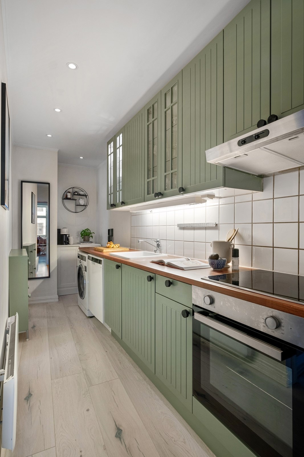 Kjøkkeninnredning med profilerte fronter, heltre benkeplate med nedfelt vaskekum. Fliser og belysning over benkeplaten. Galleribilde