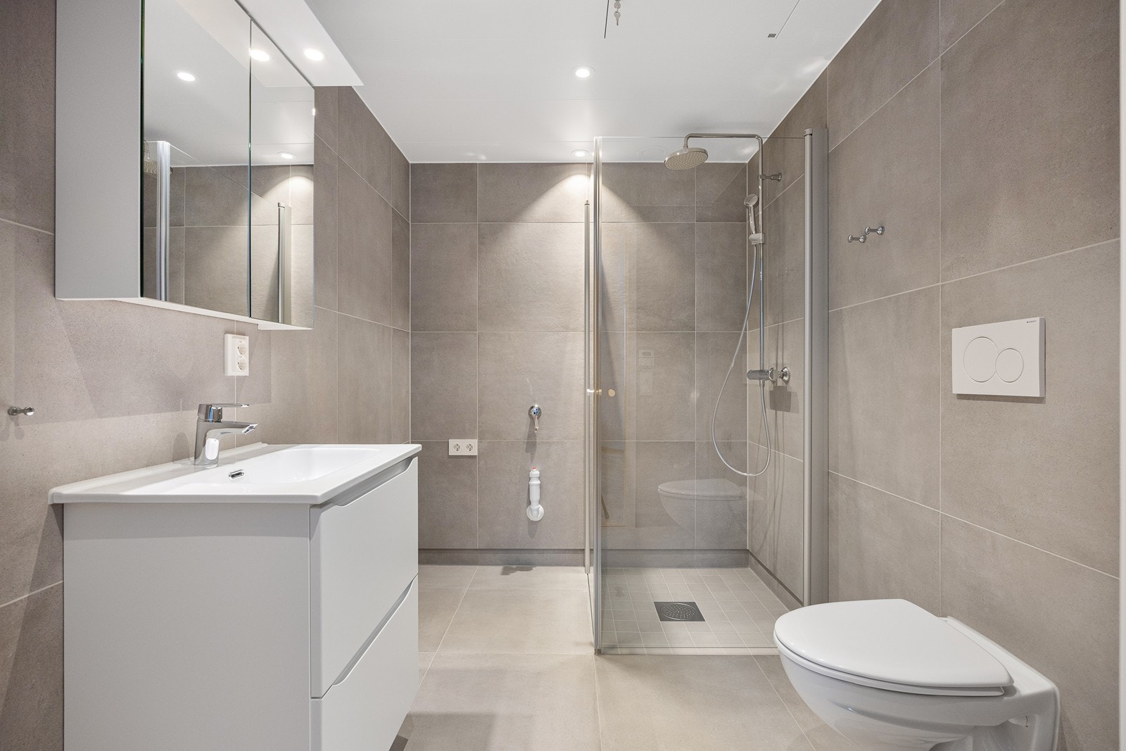 Med 60x60 flis på vegger og gulv får badet et eksklusivt preg. I dusjsonen er det mindre fliser på gulv. Galleribilde