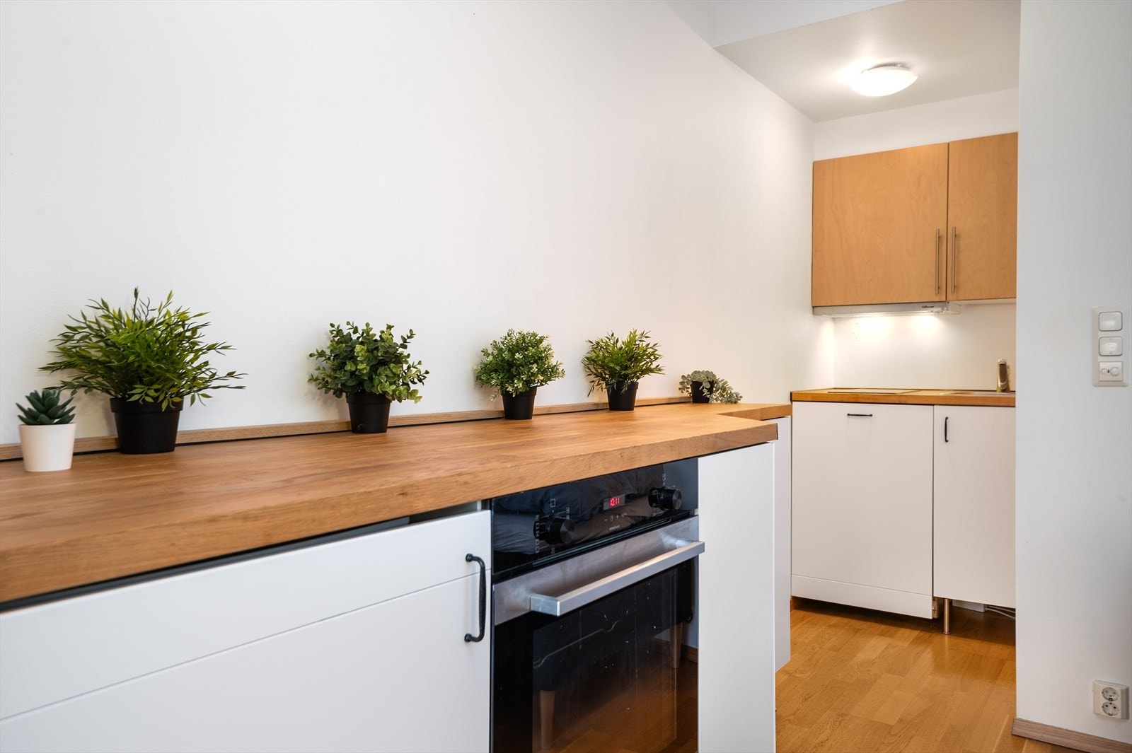 Praktisk utforming av kjøkkenet som gir fin benke- og skapplass Galleribilde