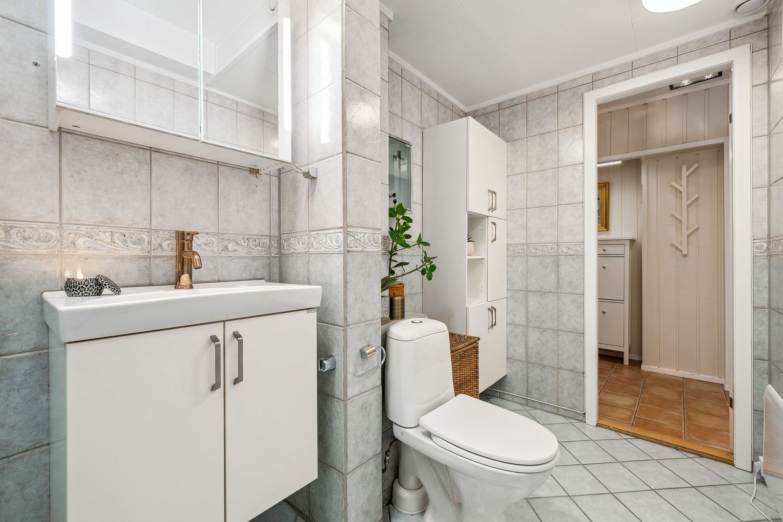 Fra entreen har man tilkomst til leilighetens baderom. Badet er av god størrelse og har flere baderomsskap for oppbevaring. Galleribilde