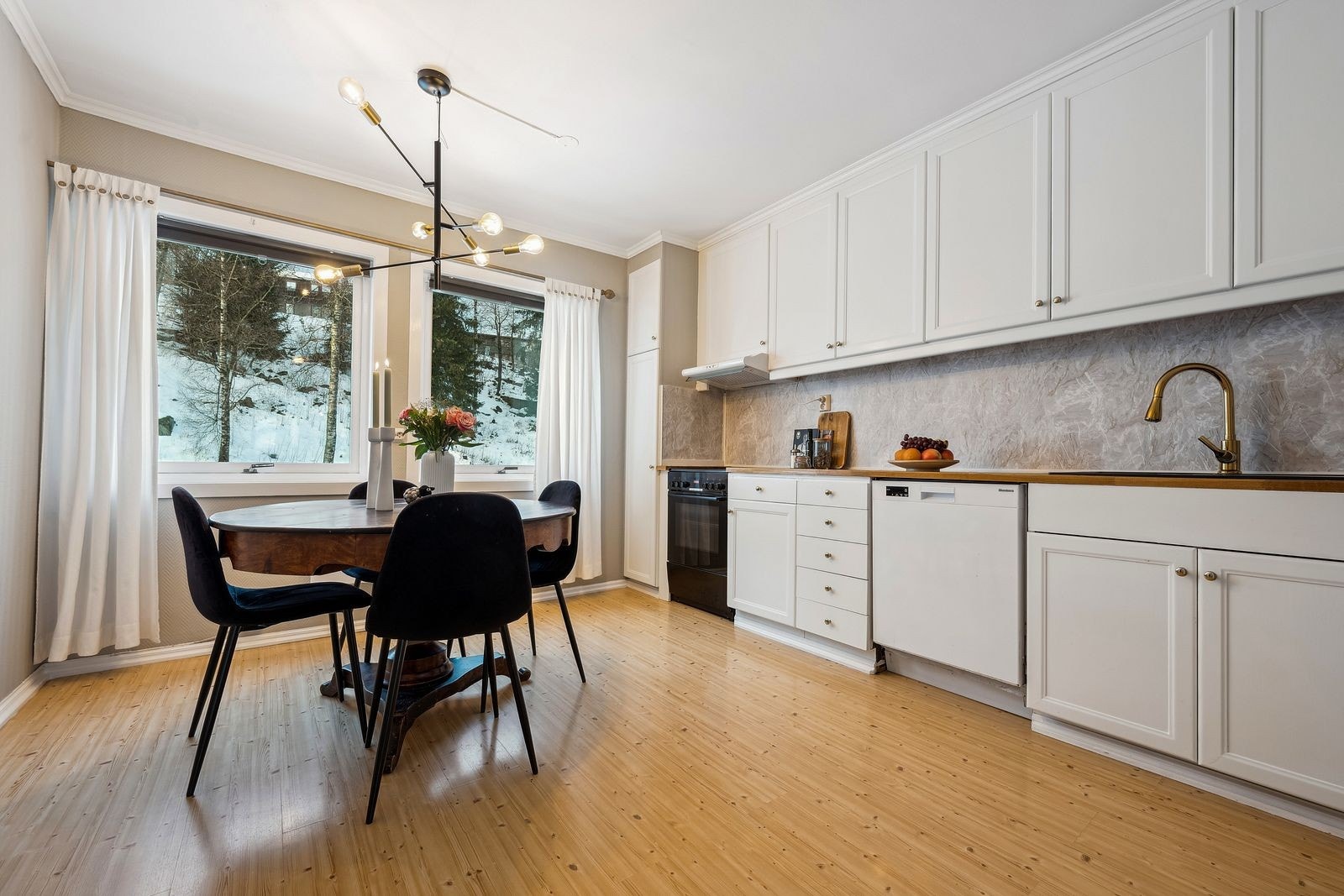 Leilighetens kjøkken er romslig og har innredning med hvite, profilerte fronter samt frittstående hvitevarer. Galleribilde