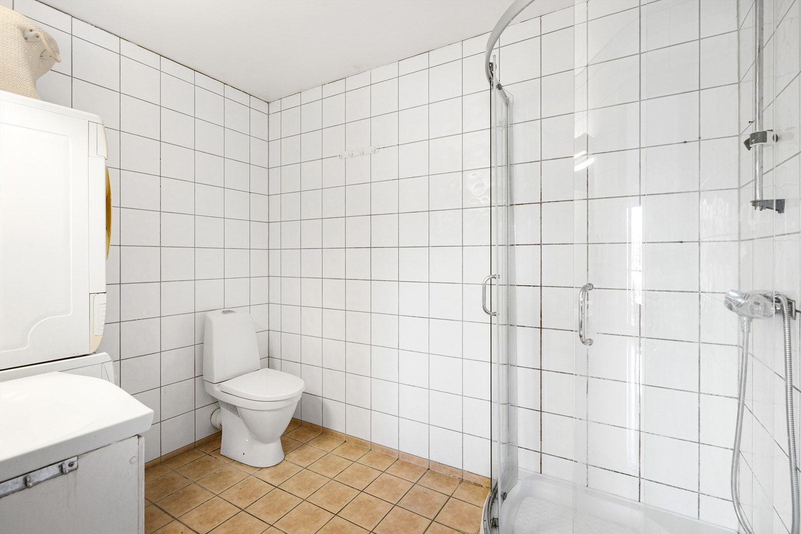 Bad med flislagte vegger og gulv. Badet har en hvit baderomsinnredning med profilerte fronter, servant i helstøpt plate som ligger oppå, kromfarget blandebatteri og et speil med belysning. Galleribilde