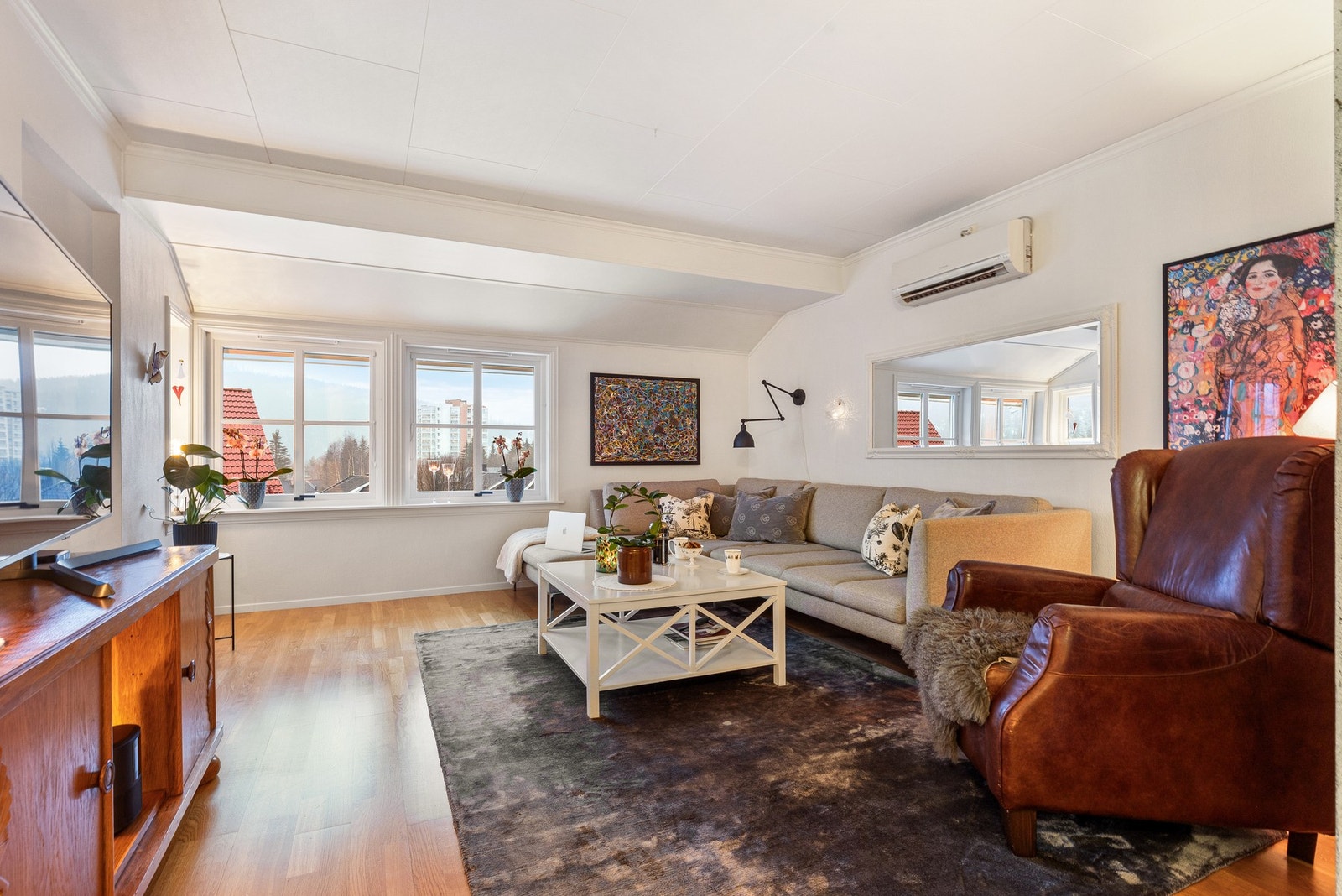 Romslig stue med parkettgulv, som har plass til både sofagruppe og andre møblementer Galleribilde