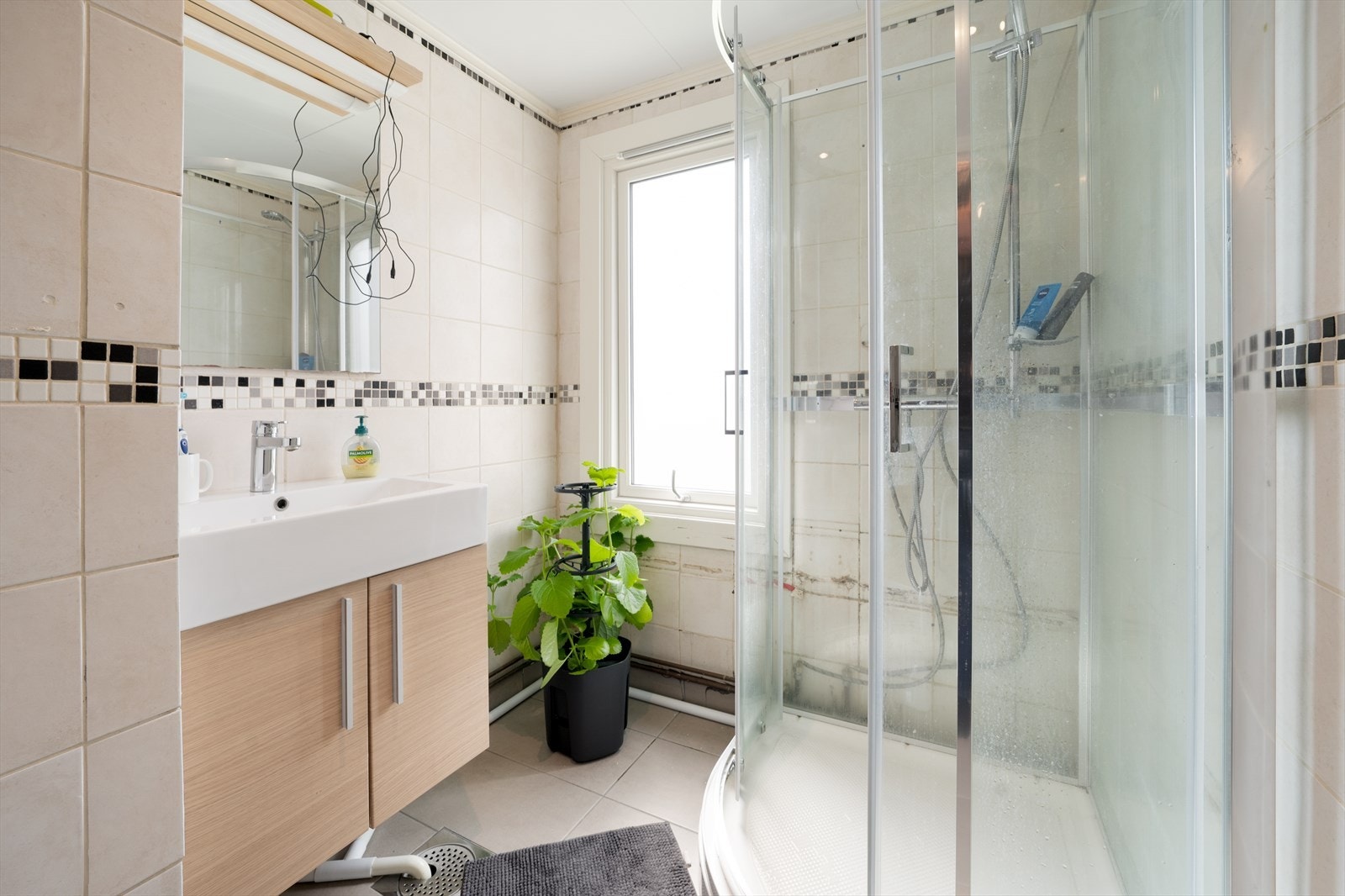 Bad på 5 kvm med flis på gulv(2023) og vegger. Her er det toalett, dusjkabinett(2023) og innredning med heldekkende hvit vask, underskap med slette fronter og speil. På badet er det også opplegg for vaskemaskin. Varmekabler i gulv og avtrekksventil i tak. Galleribilde