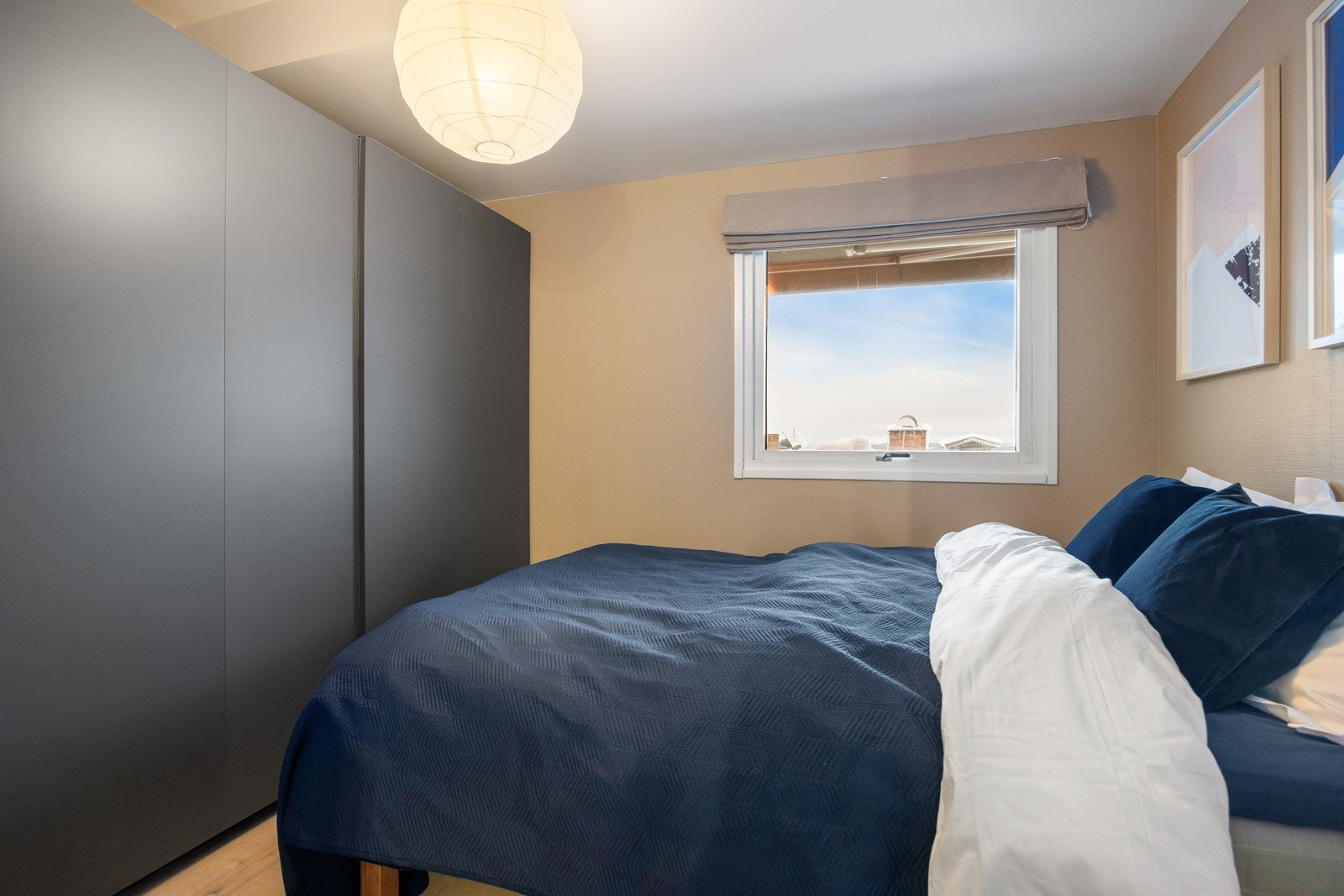 Langs den ene langveggen er det etablert en plassbygd skyvedørsgarderobe med mørke fronter. Galleribilde