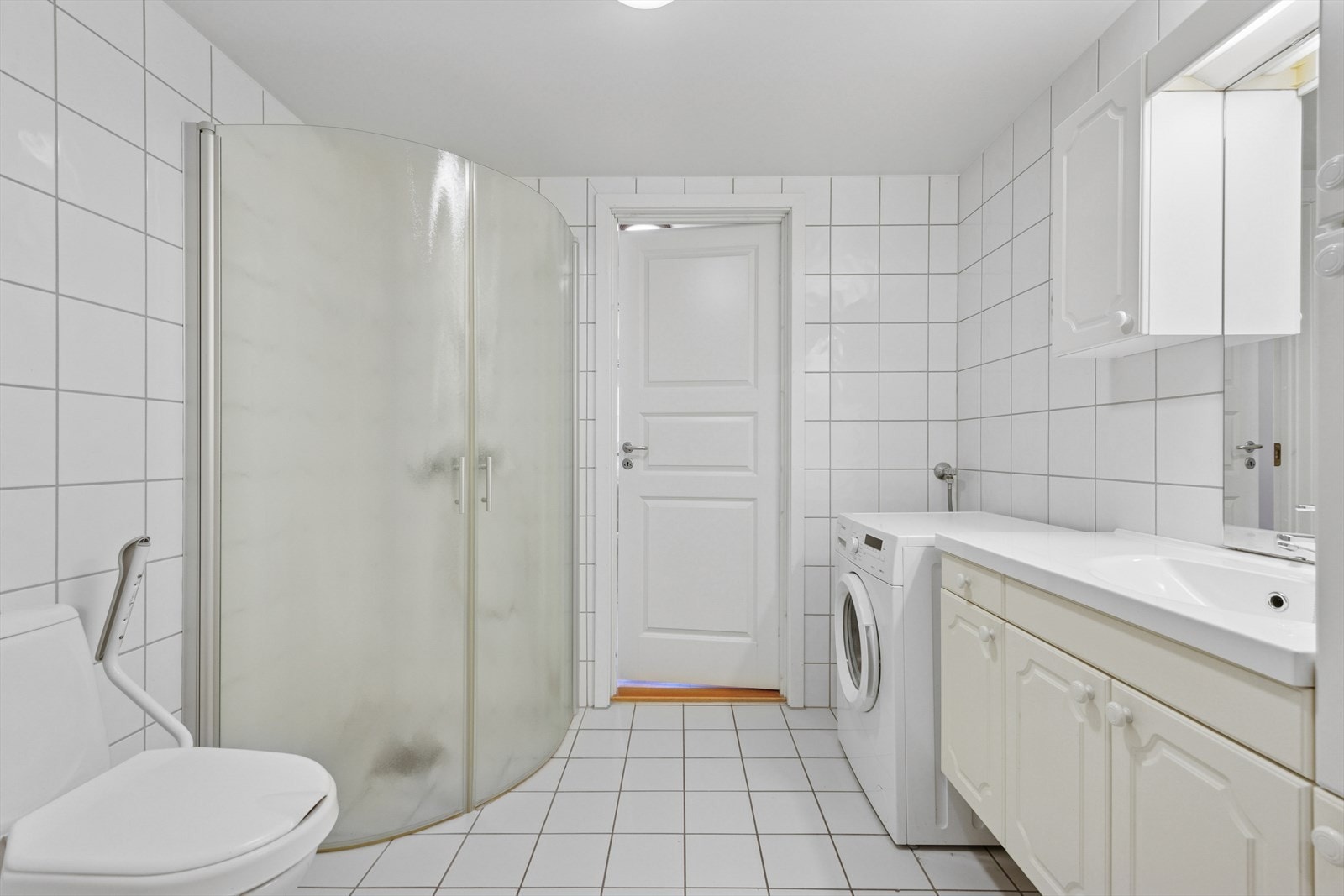 Badet er romslig og innredet med servant med skap, WC, dusjsone med foldedører og opplegg for vaskemaskin. Galleribilde