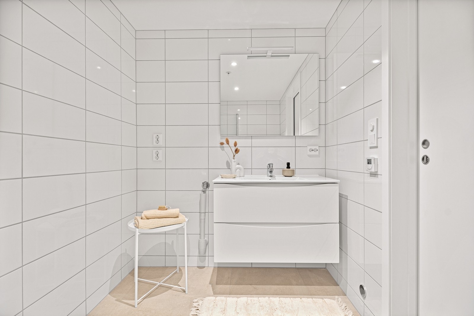 Det er servant med innredning, speil med lys samt opplegg til vaskemaskin og tørketrommel. Galleribilde