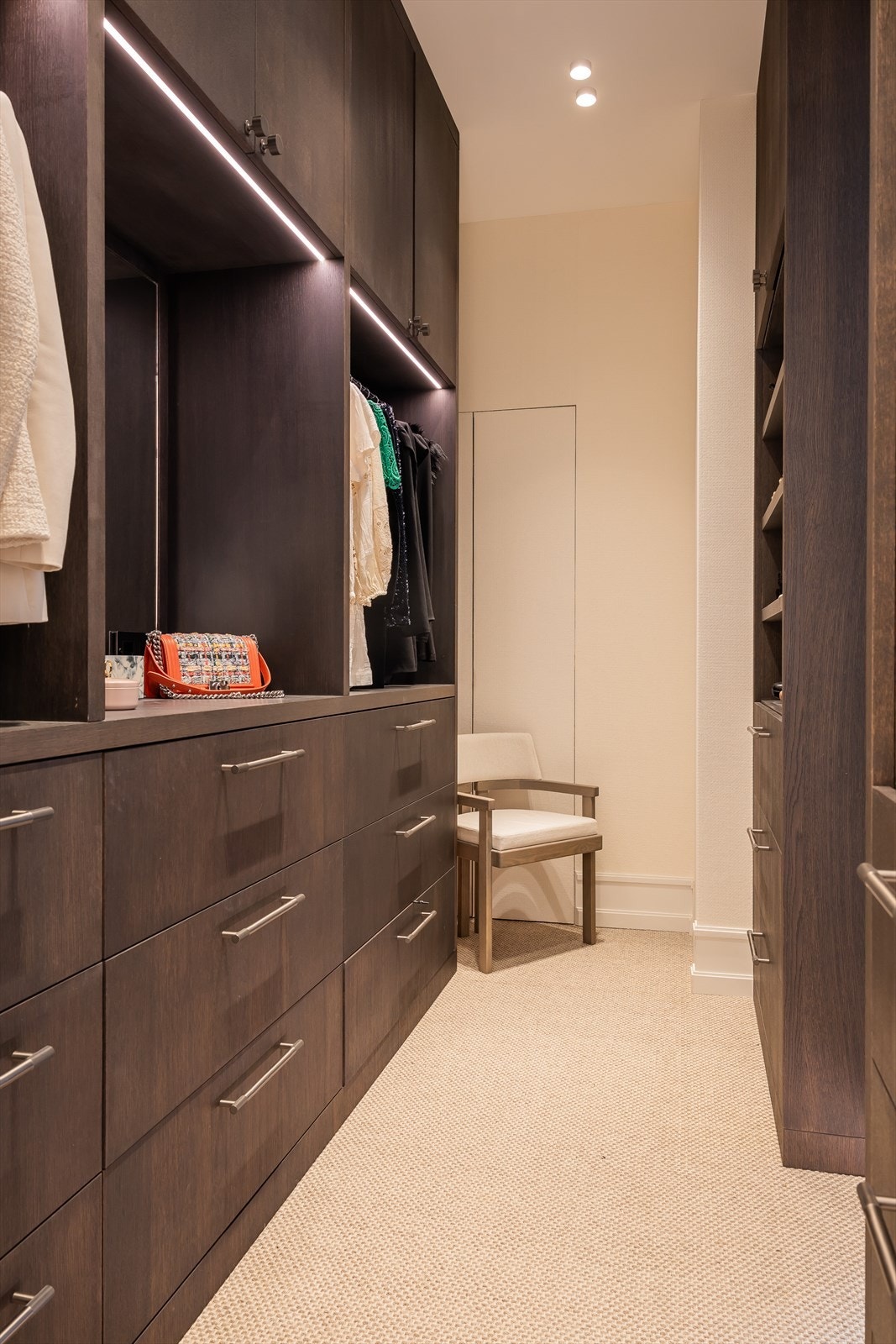 Walk-in-closet med downlights i himling, lyst ullteppe på gulv og en eksklusiv naturtapet fra Thibaut på veggene. Galleribilde
