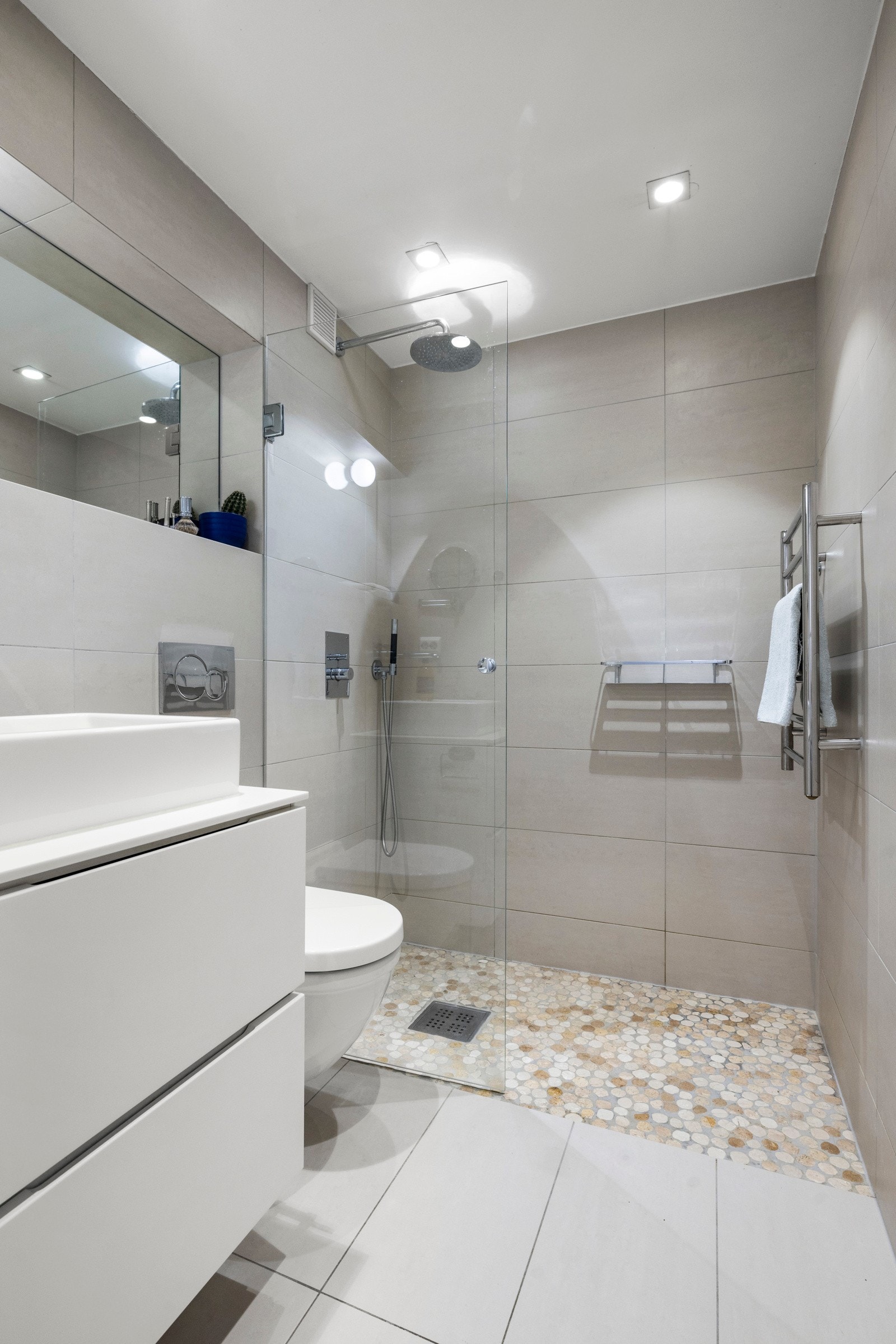 Flislagt bad med varmekabler, dusjnisje, veggmontert servantinnredning og vegghengt toalett Galleribilde