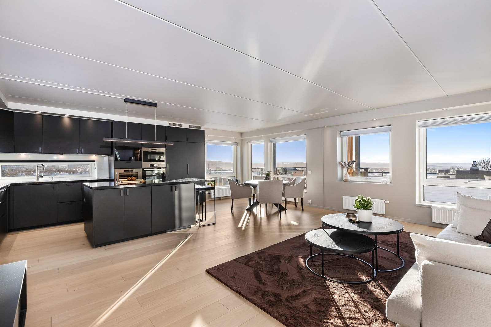 Kjøkkenet har sorte, glatte fronter og benkeplate i sten. Galleribilde