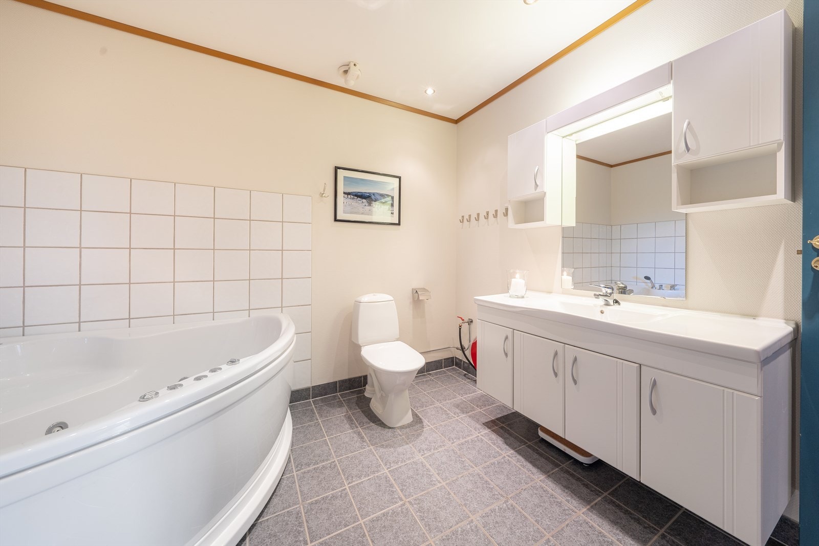 Hovedbadet på 8,4 m2 har flislagt gulv med varmekabler. Her er en romslig innredning med heldekkende servant samt sideskap og speil med overlys og el-stikk. Badet er også innredet med hjørneboblekar og toalett, samt at det er opplegg for vaskemaskin. Galleribilde