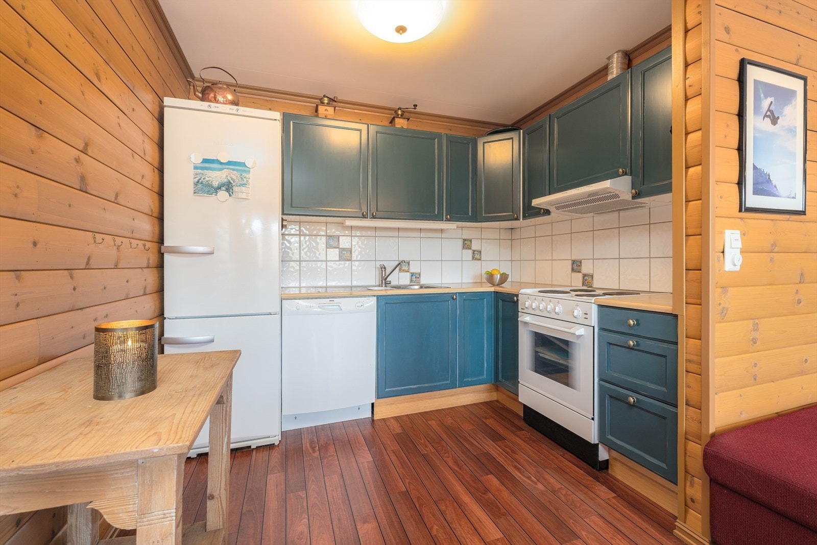 På kjøkkenet er det innredning med blåmalte, profilerte fronter samt benkeplater med laminerte overflater. Mellom benk og overskap er det flislagt. Galleribilde