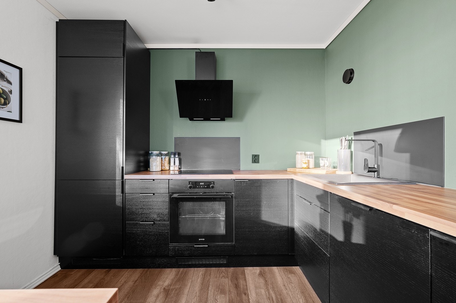 Integrerte hvitevarer som induksjonstopp, kjøkkenventilator, stekeovn, kjøleskap med frysedel og oppvaskmaskin. Galleribilde