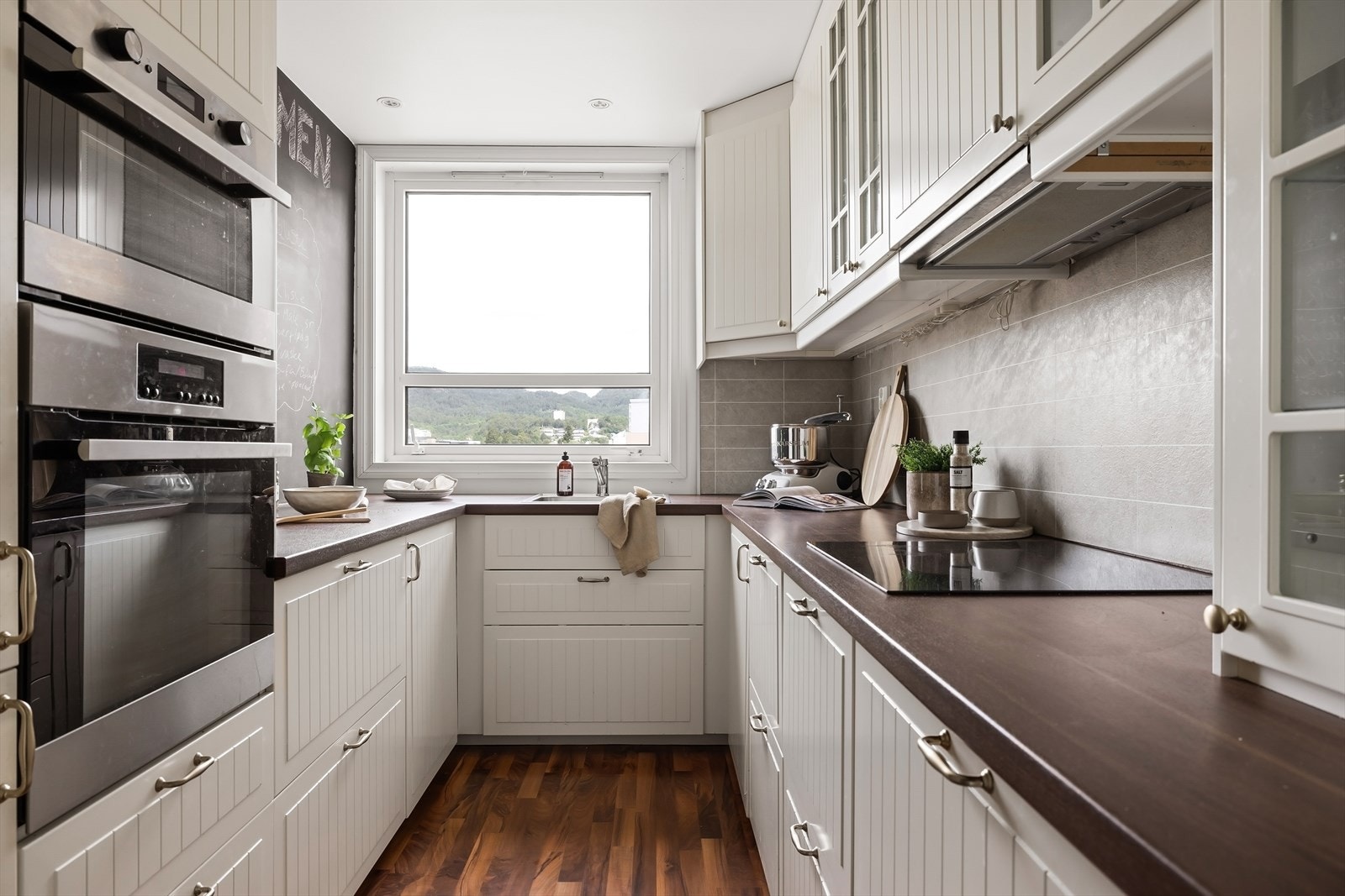 Flott kjøkken med utsikt. her er det profilerte hvite fronter og integrert induksjonsplatetopp, stekeovn, mikrobølgeovn, kjøl- og frys og oppvaskmaskin. Galleribilde