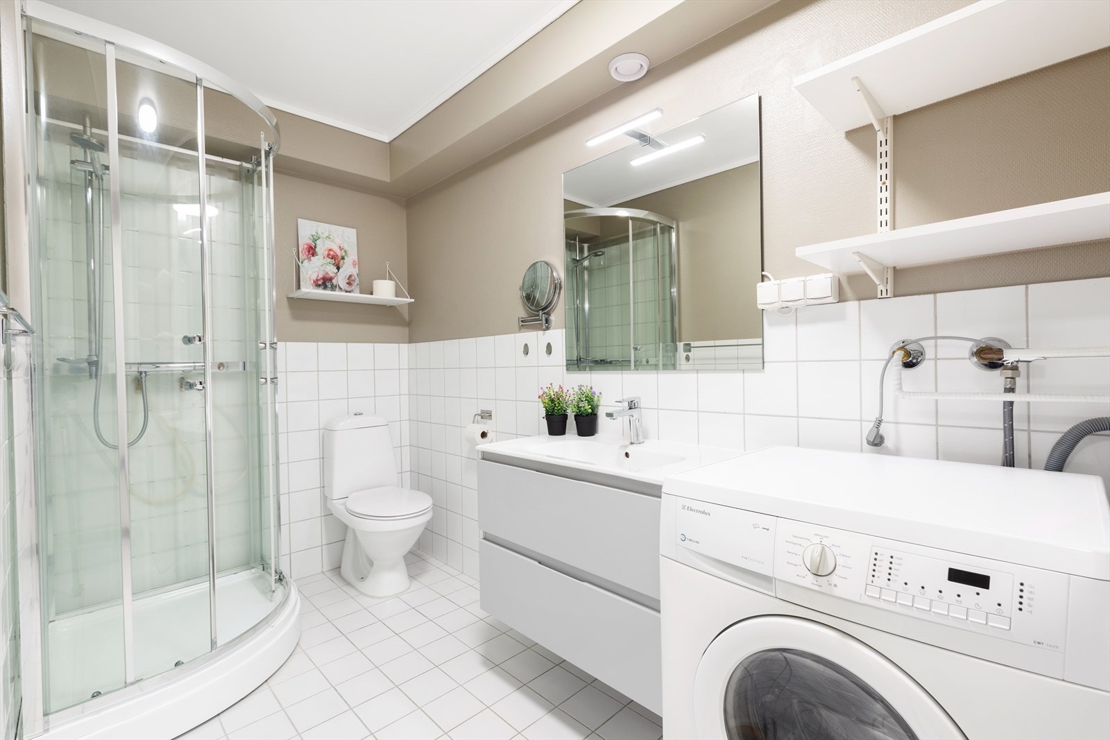 Lyst og pent bad med dusjkabinett, toalett og baderomsinnredning med heldekkende servant. Galleribilde