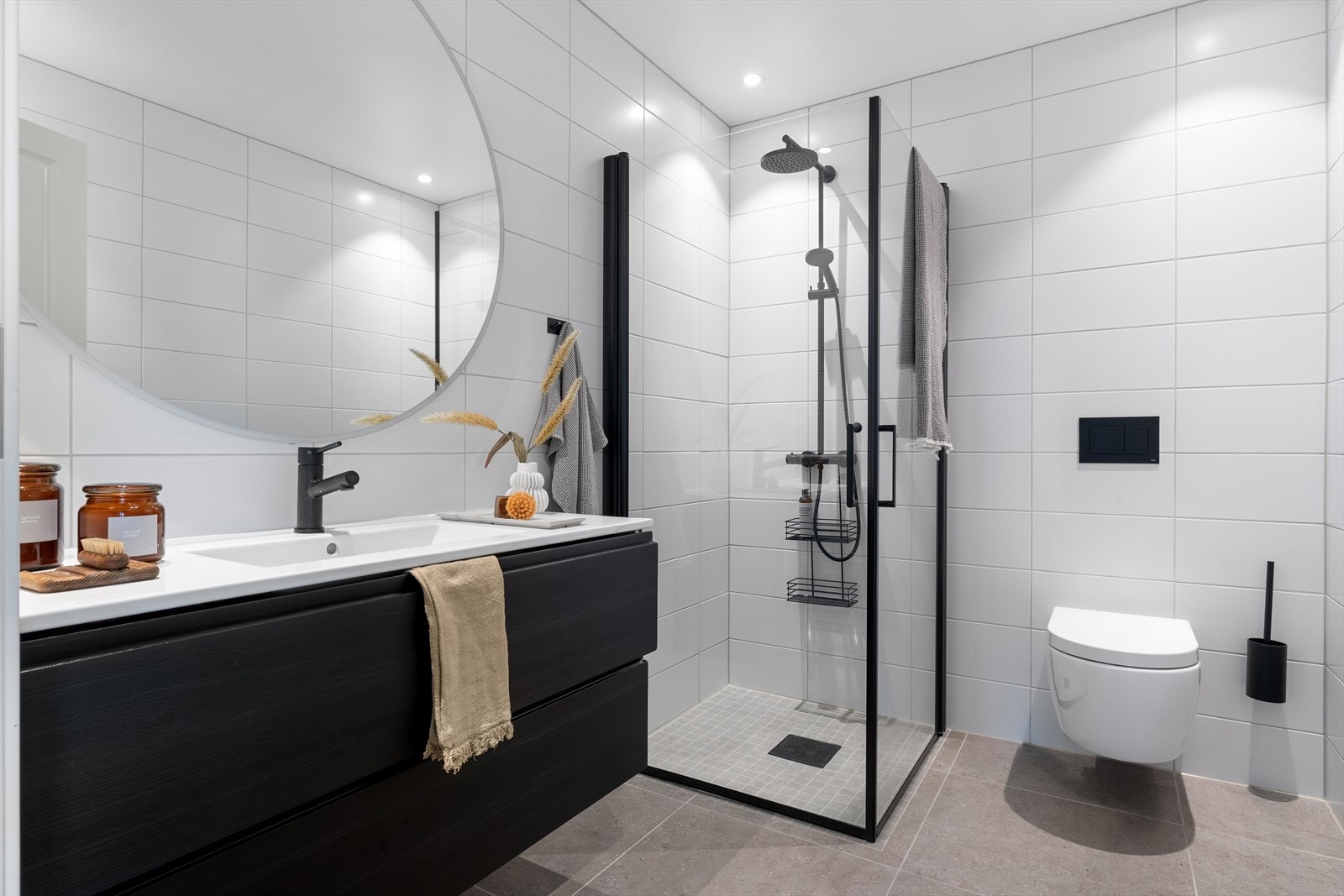 Videre innredet med servant i møbel, speil med lys, vegghengt toalett og dusj med glassdører. Galleribilde