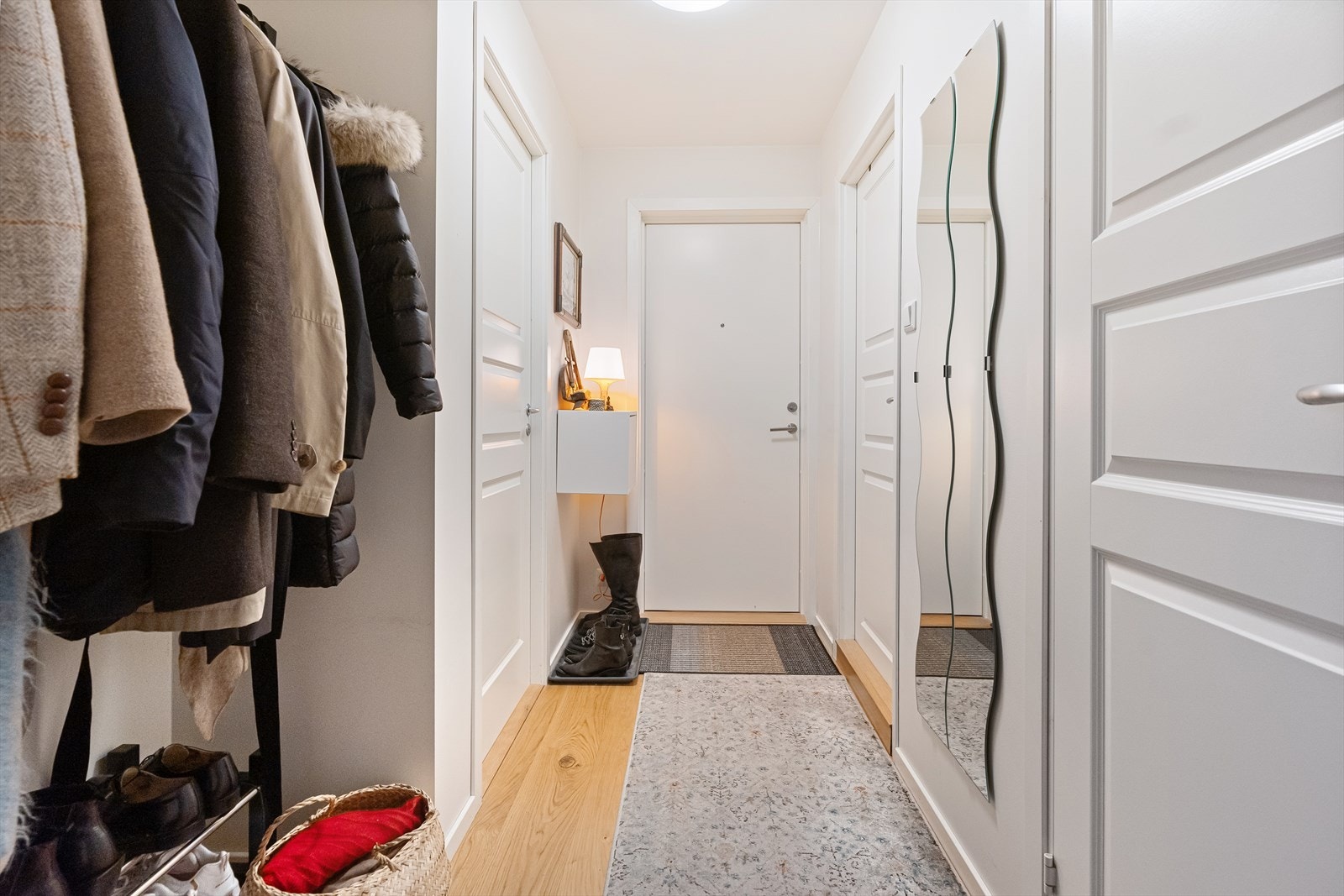Velkommen til en lys og innbydende entré med speil og praktisk oppbevaring for yttertøy og sko. Galleribilde