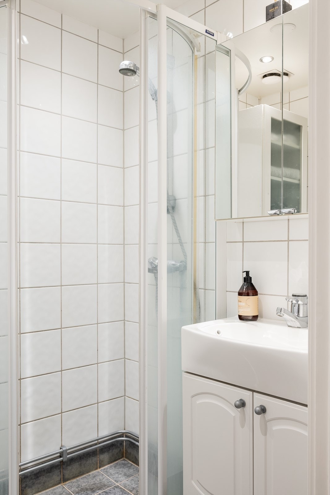 Baderommet med lyse fliser på veggene og stilige grå fliser på gulvet. Galleribilde