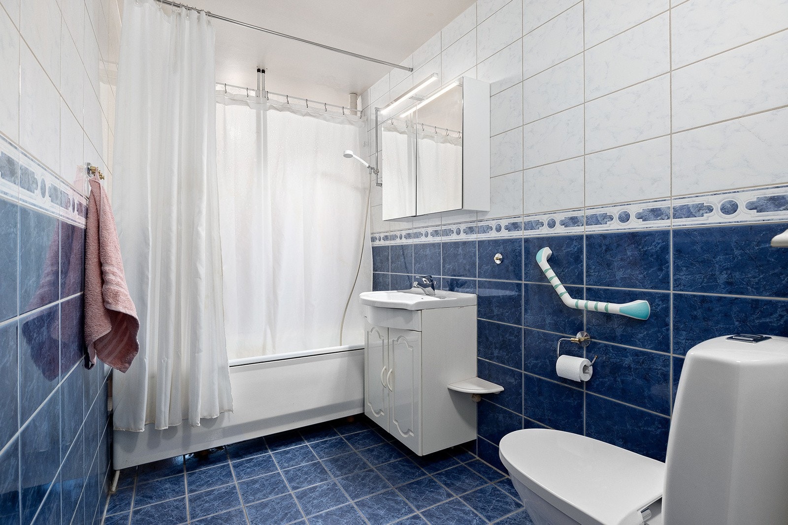 Flislagt bad med servant m/over- og underskap, klosett og badekar. Badet skal pusses opp i regi av borettslaget i 2026. Galleribilde