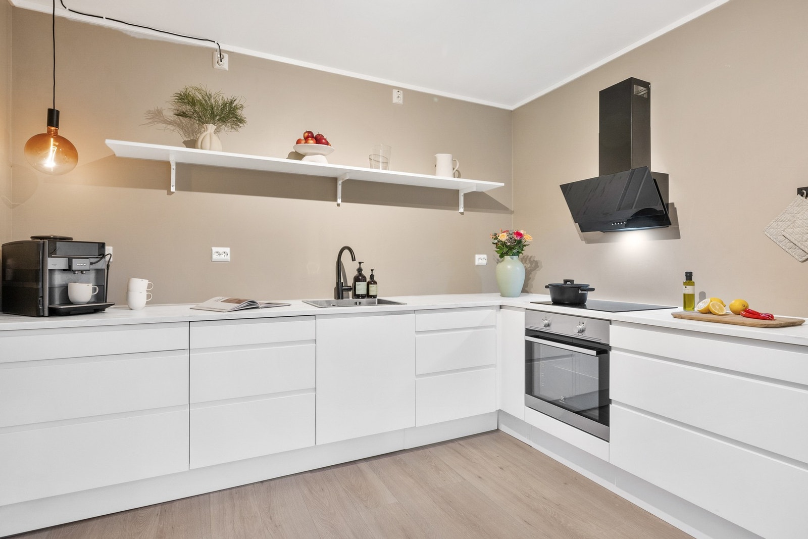 Kjøkkeninnredning med glatte fronter og benkeplaten er av laminat med nedfelt servant og platetopp. Galleribilde