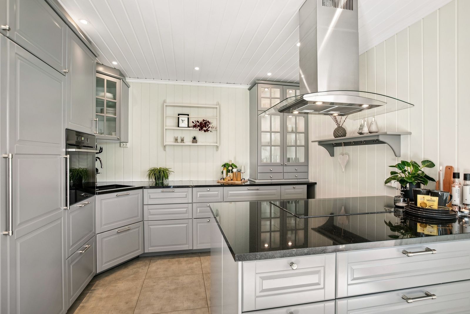 Romslig og innholdsrikt kjøkken av pen og klassisk karakter med fliser på gulv og gulvvarme. Galleribilde