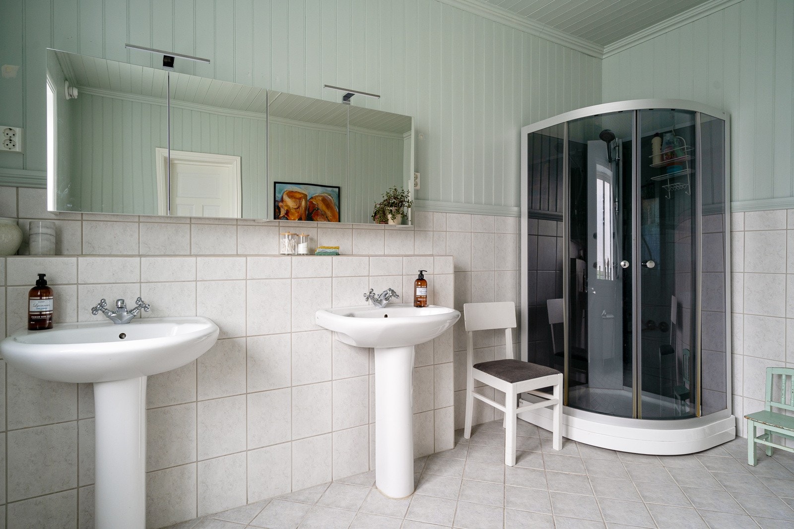 Stort, flislagt bad, utstyrt med dusjkabinett, to servanter og toalett. Galleribilde