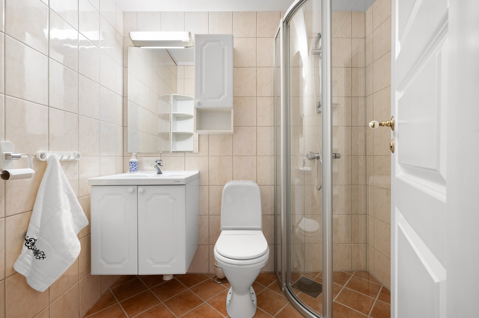 Badet er målt til 3,3m² og er helfliset med varmekabler i gulvet. Badet inneholder toalett, helstøpt servant, skap under servant med profilerte fronter, dusjdører i klart glass og opplegg for
vaskemaskin. Galleribilde