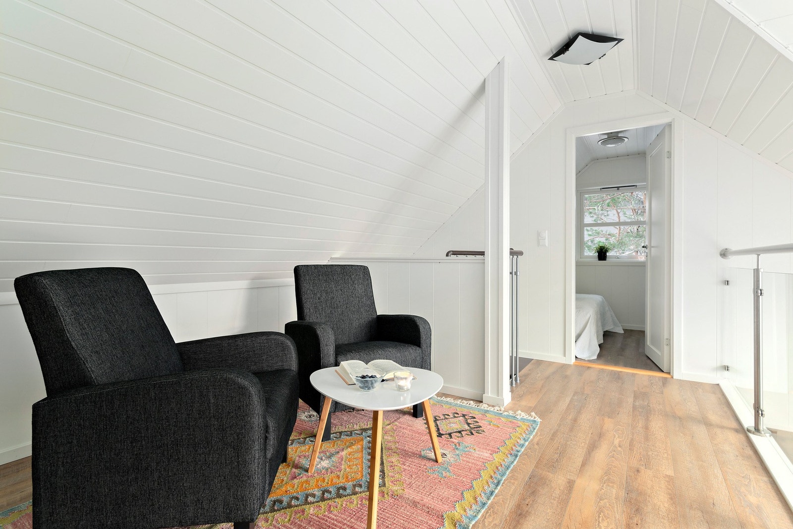 Loftstue med flotte gulv og lyse overflater. Legg merke til glassrekkverk til åpen himling ned mot stue. Galleribilde