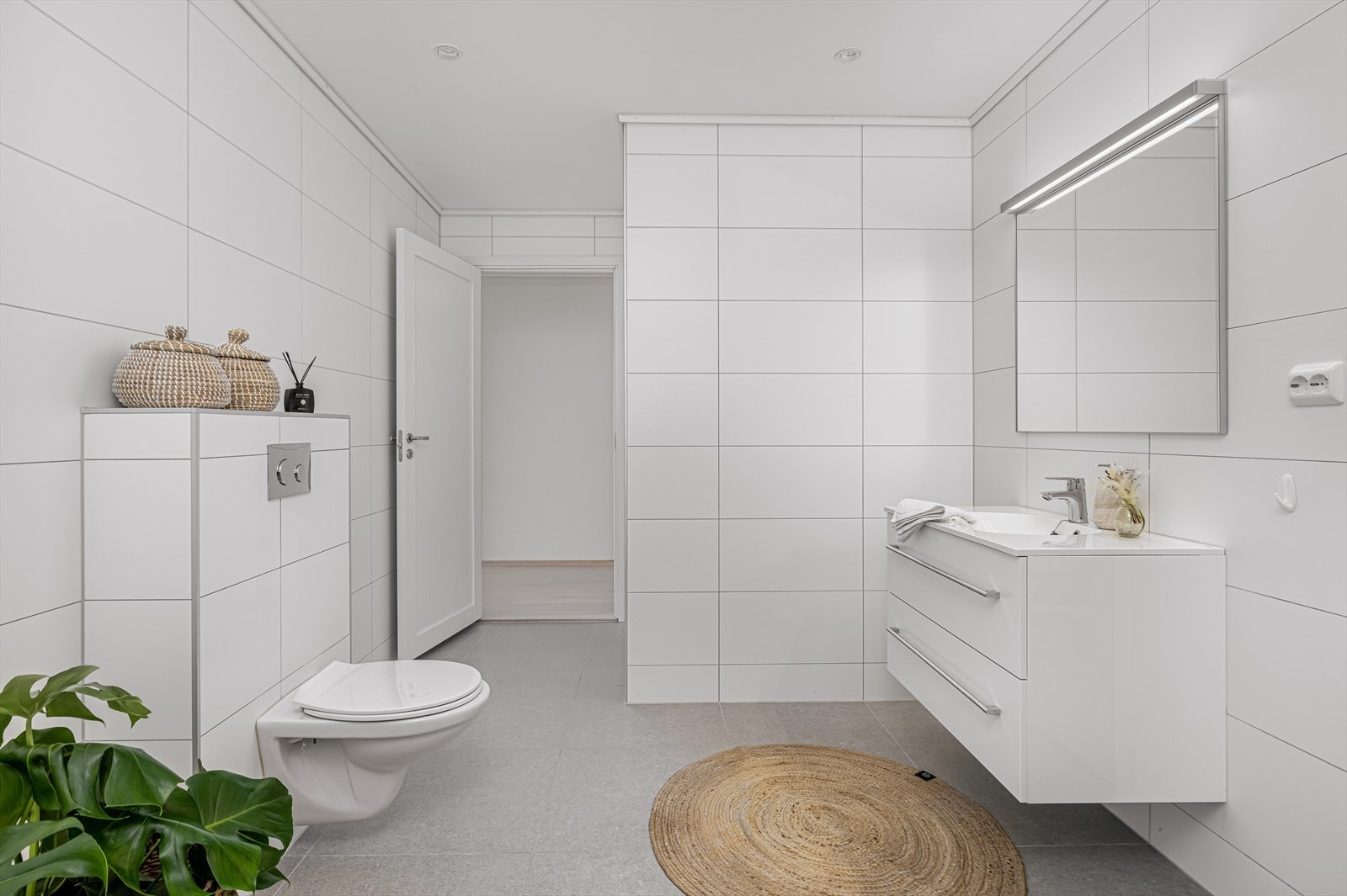 Pen innredning i høyglans, med dype skuffer og heldekkende servantplate, samt stort speil med overlys og el-stikk på vegg. Galleribilde