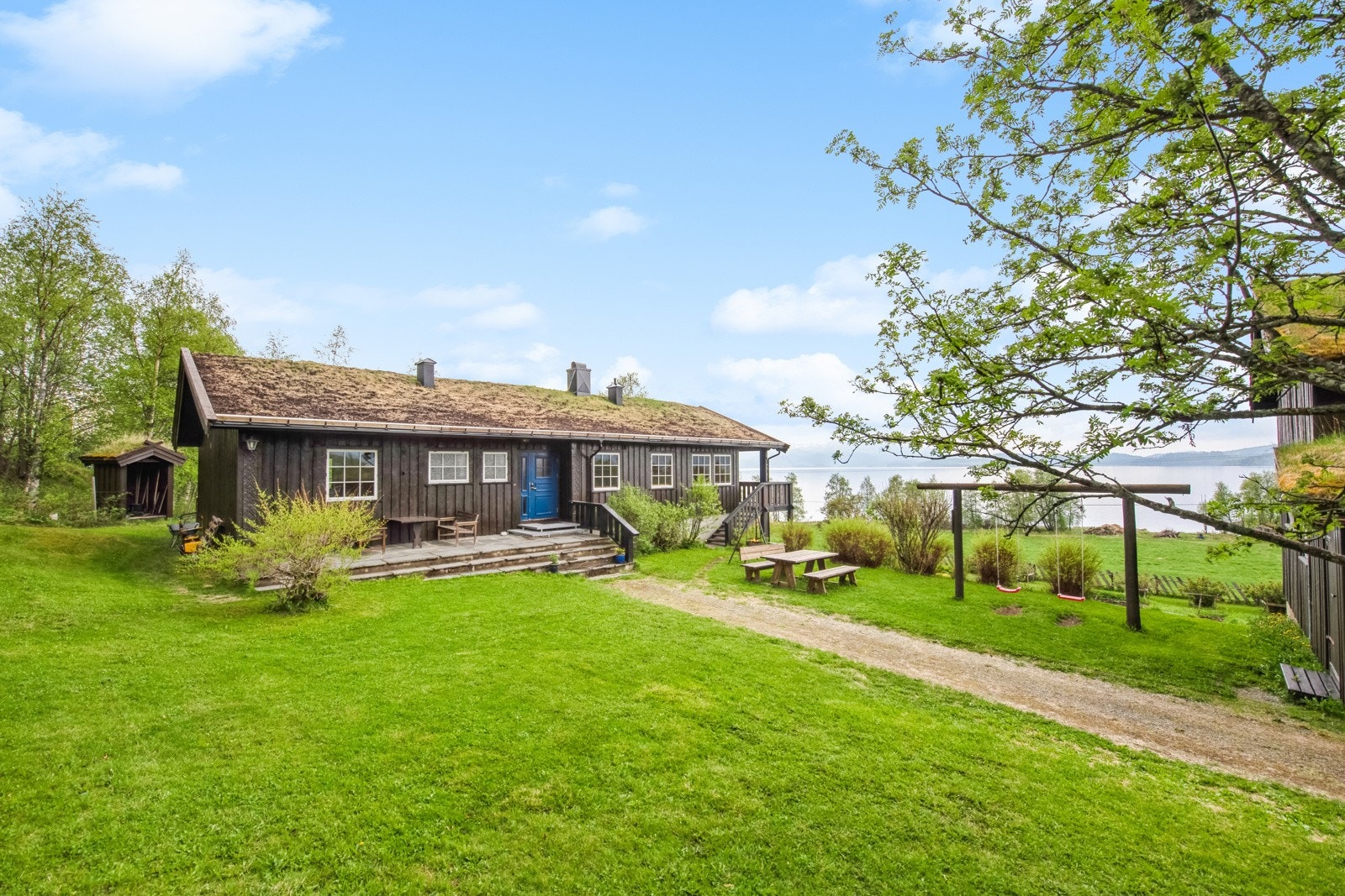 Frodig tun innrammet av bygningsmasse, beplantning og trær Galleribilde