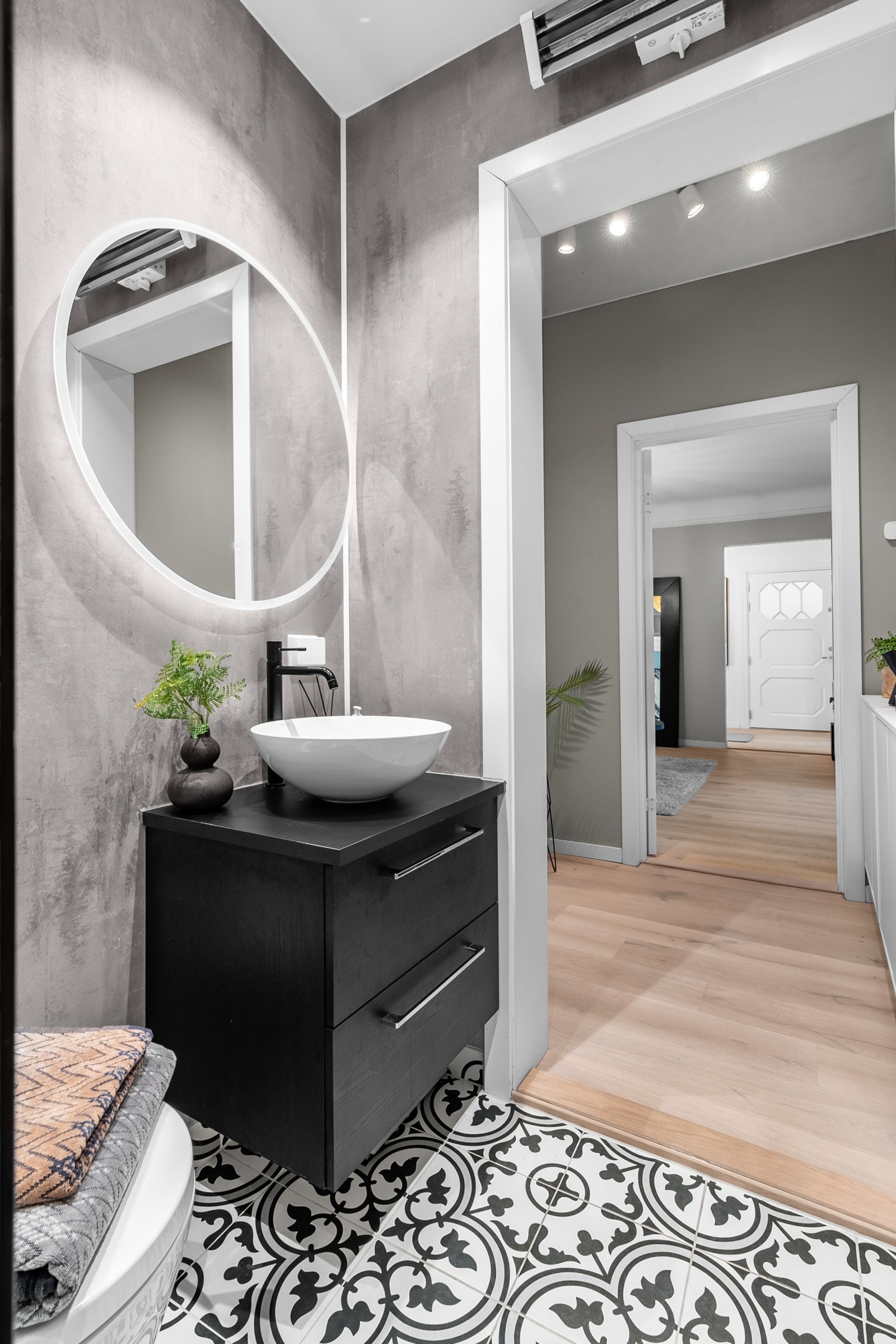 Innredningen består av en en bolleservant på mørk skuffeseksjon, rundt speil med integrert belysning og et veggmontert toalett. Galleribilde