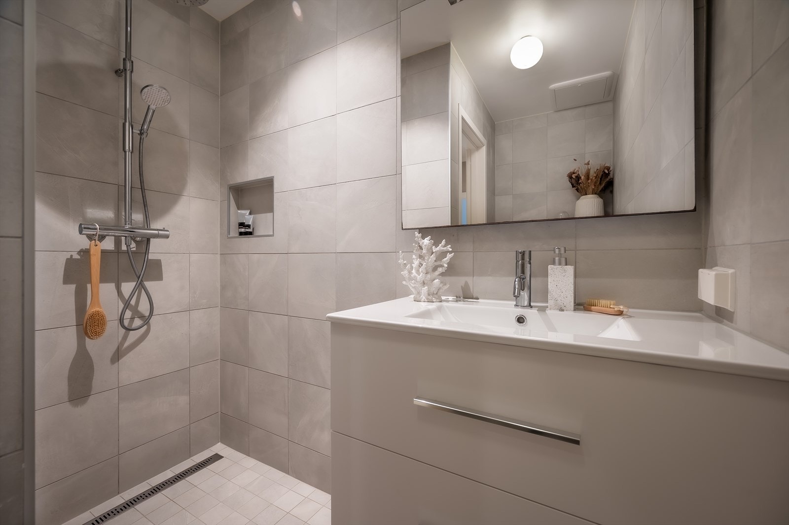 Lekkert bad med flislagte overflater, innfelte lys og elektriske varmekabler. Galleribilde