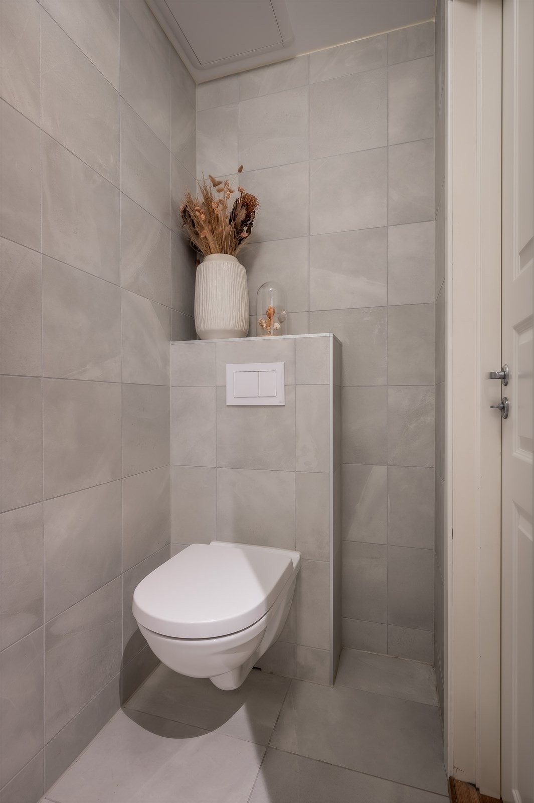 Badet er innredet med servant, speil, veggmontert klosett og dusj direkte på gulv med termostat batteri. Galleribilde