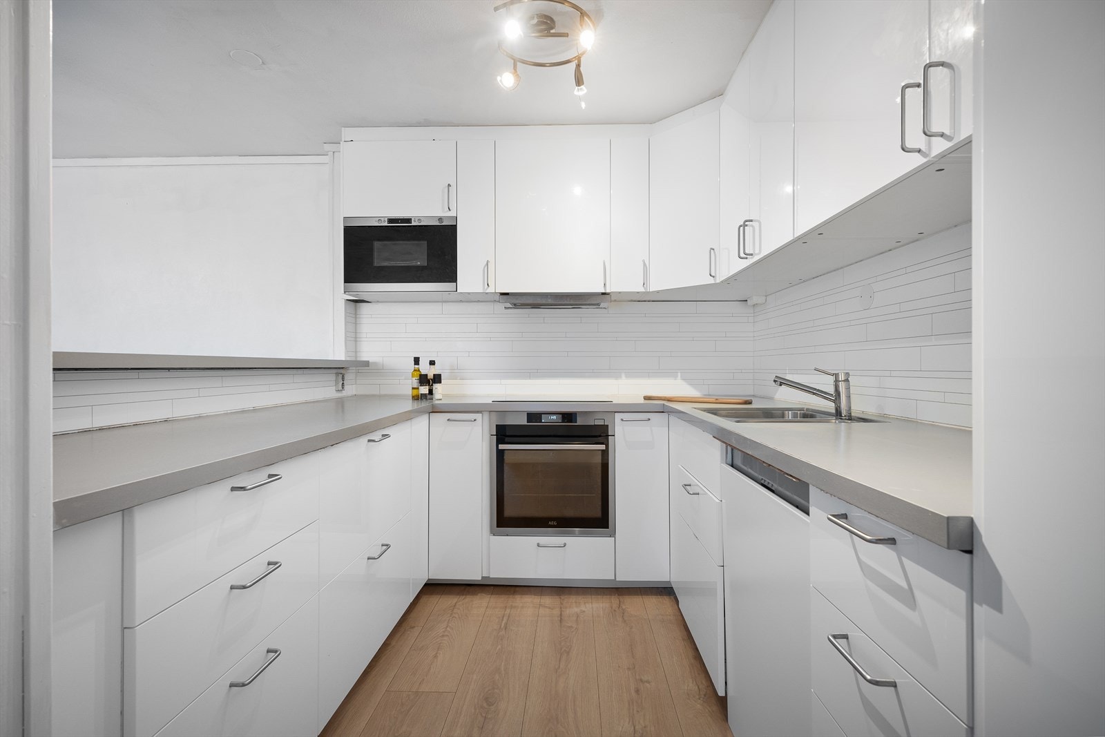 Kjøkkenet har hvite fronter og laminat benkeplate Galleribilde