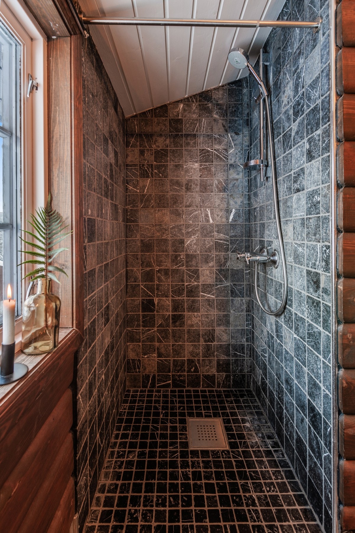 Badet har en stor, flislagt dusj der spafeelingen kommer krypende Galleribilde
