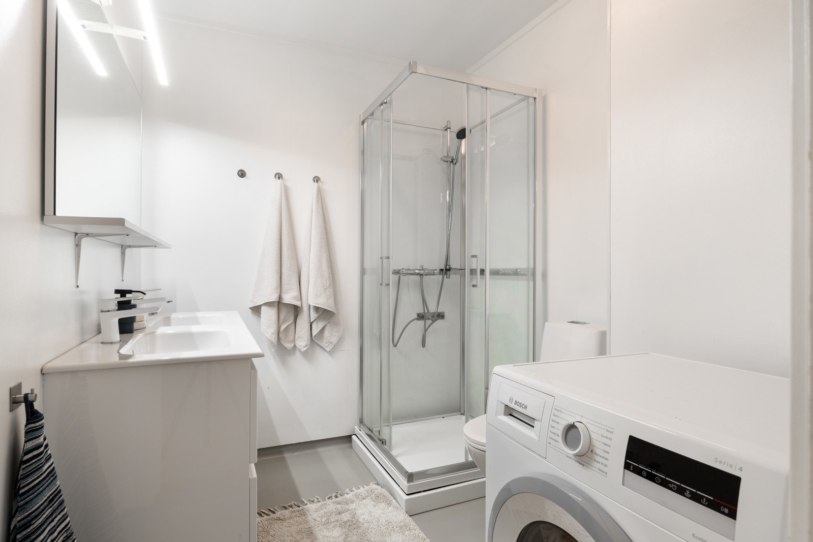 Romslig baderom med opplegg for vaskemaskin. Galleribilde