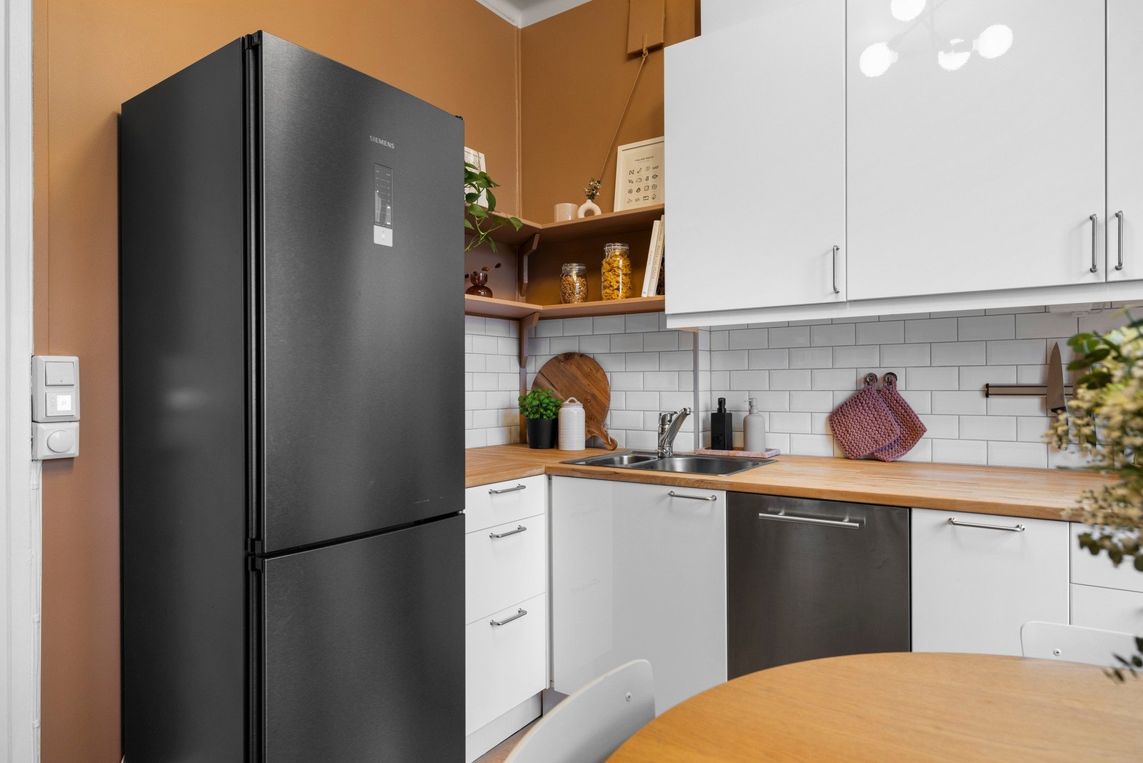 Kjøkkeninnredning med høyglans, bøk benkeplater, oppvaskkum, hetteventilator, fliser over benk, belysning under overskap og integrert oppvaskmaskin (45 cm). Galleribilde