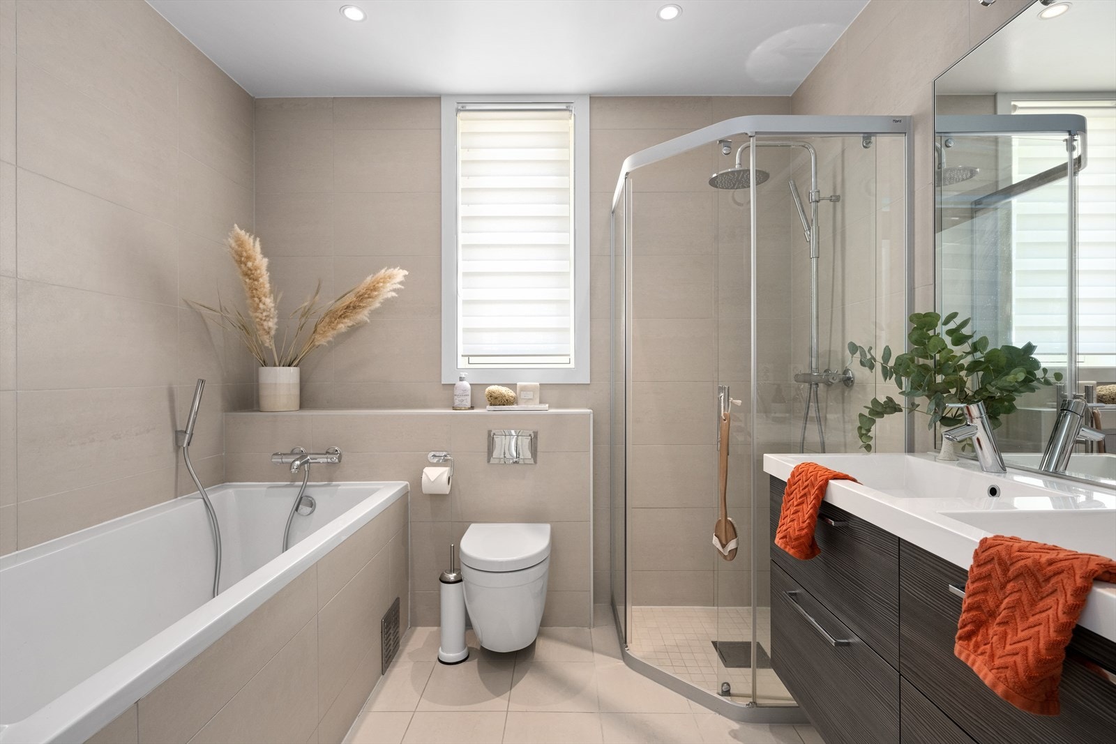 Badet tilhørende hovedsoverommet har flislagte overflater og gulvvarme - Rommet er innredet med badekar, dusjhjørne, vegghengt toalett og baderomsinnredning med dobbel servant Galleribilde